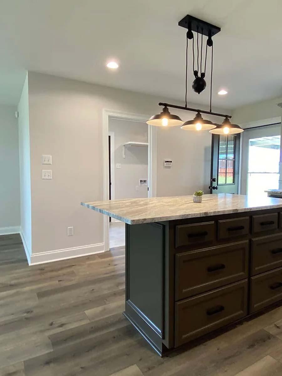 Kitchen island with granite countertop, dark wood cabinets and drawers, and a rustic pulley pendant light above.