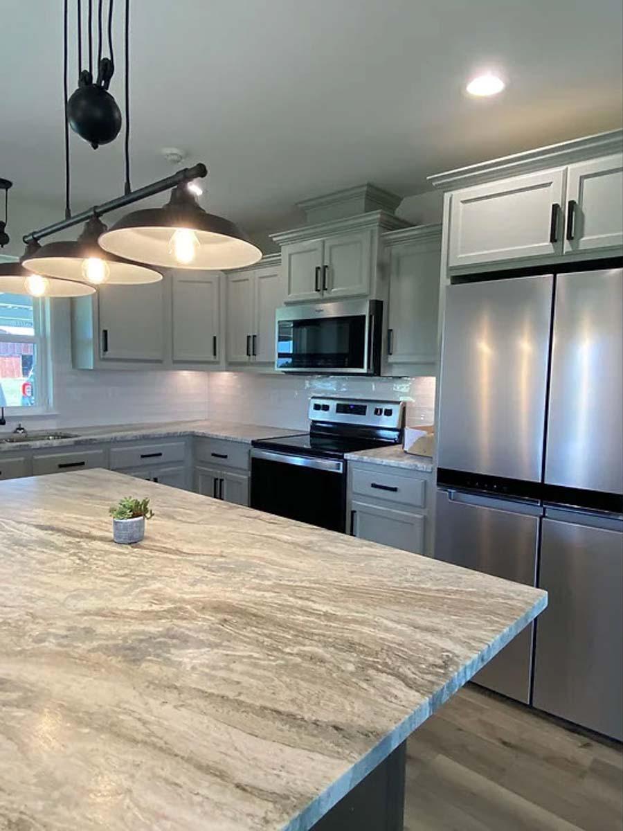 Kitchen with island featuring a stone countertop, gray cabinetry, stainless steel appliances, and industrial pendant lighting.
