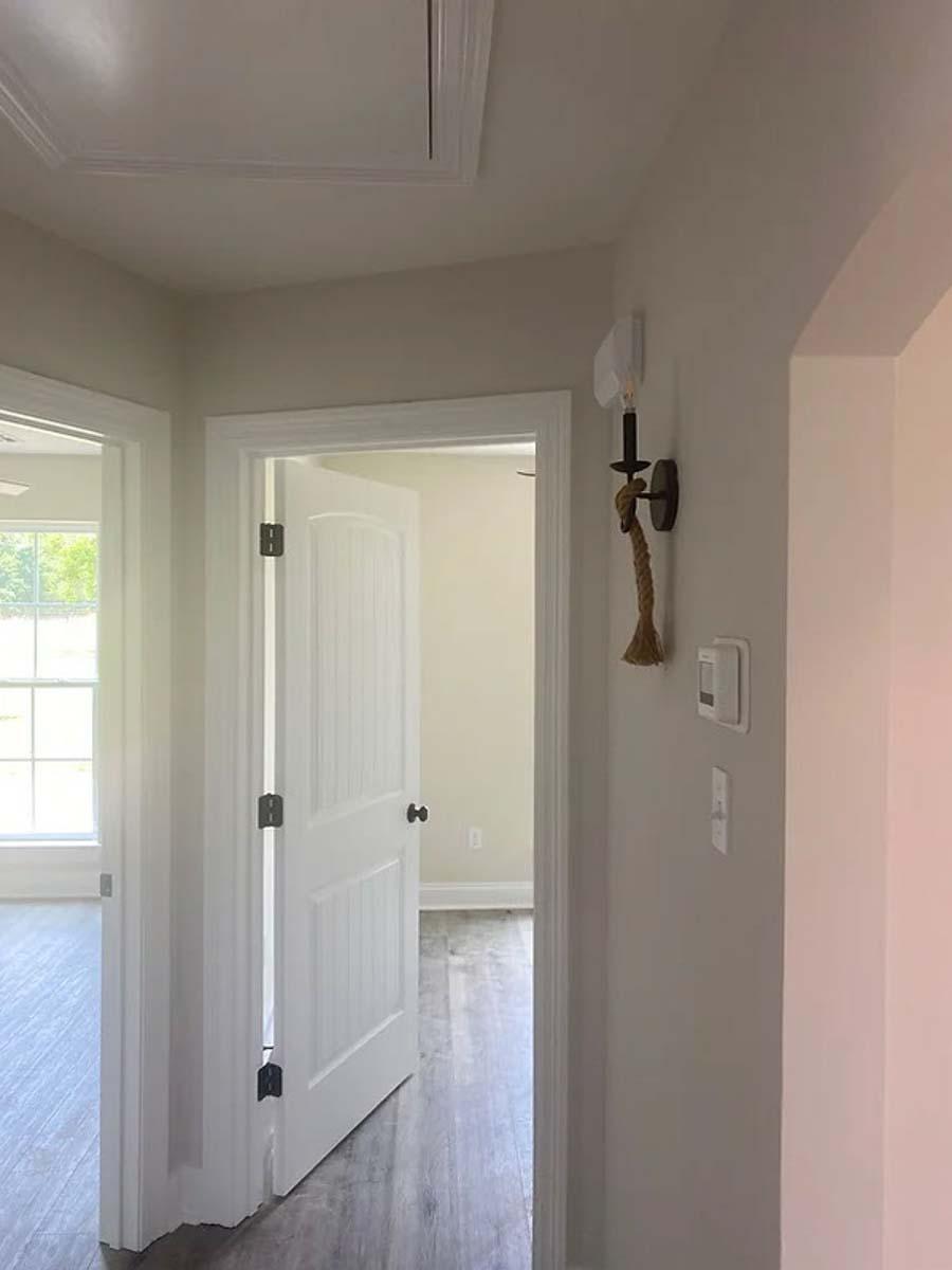 Interior hallway showing a door ajar, a wall sconce with rope detail, and a ceiling access panel.