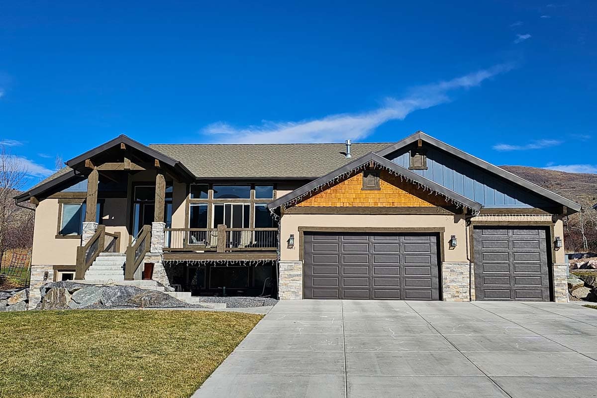 House plan exterior. Two-story with Craftsman details. Features include a covered porch, multiple gables, and a three-car garage.