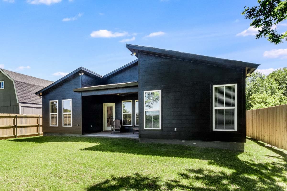 Modern house plan exterior with dark horizontal siding, asymmetrical rooflines, covered patio, and numerous windows.
