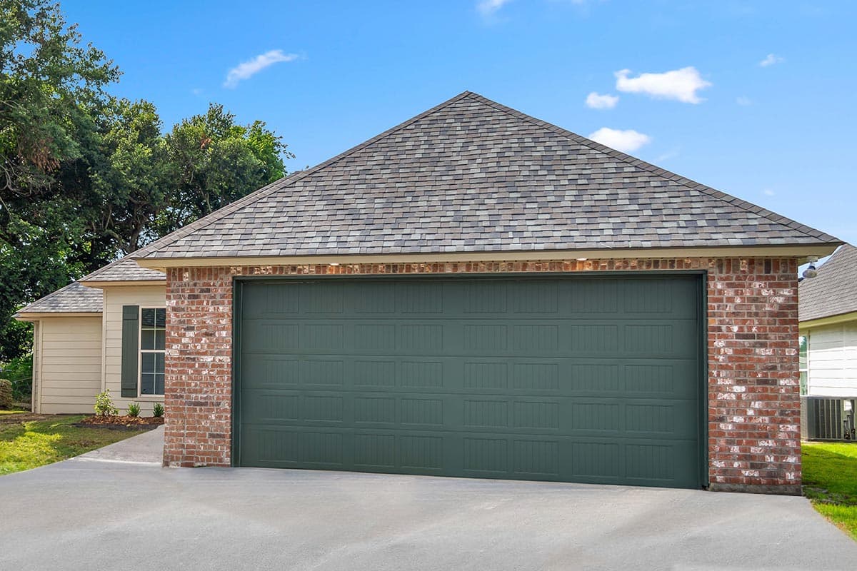 House plan exterior: One-story garage with brick facade, gable roof, and green overhead door.
