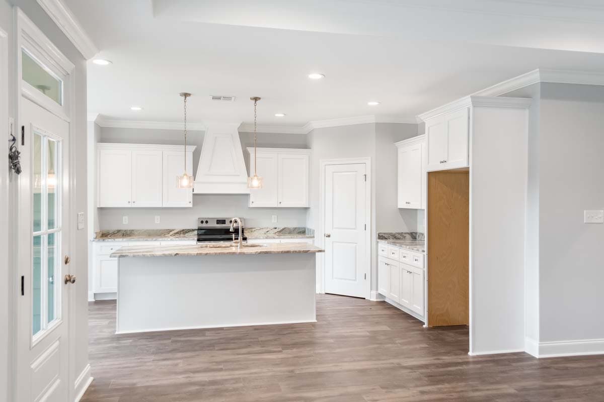 Kitchen with white cabinets, island, granite countertops, stainless steel range, and pendant lighting.