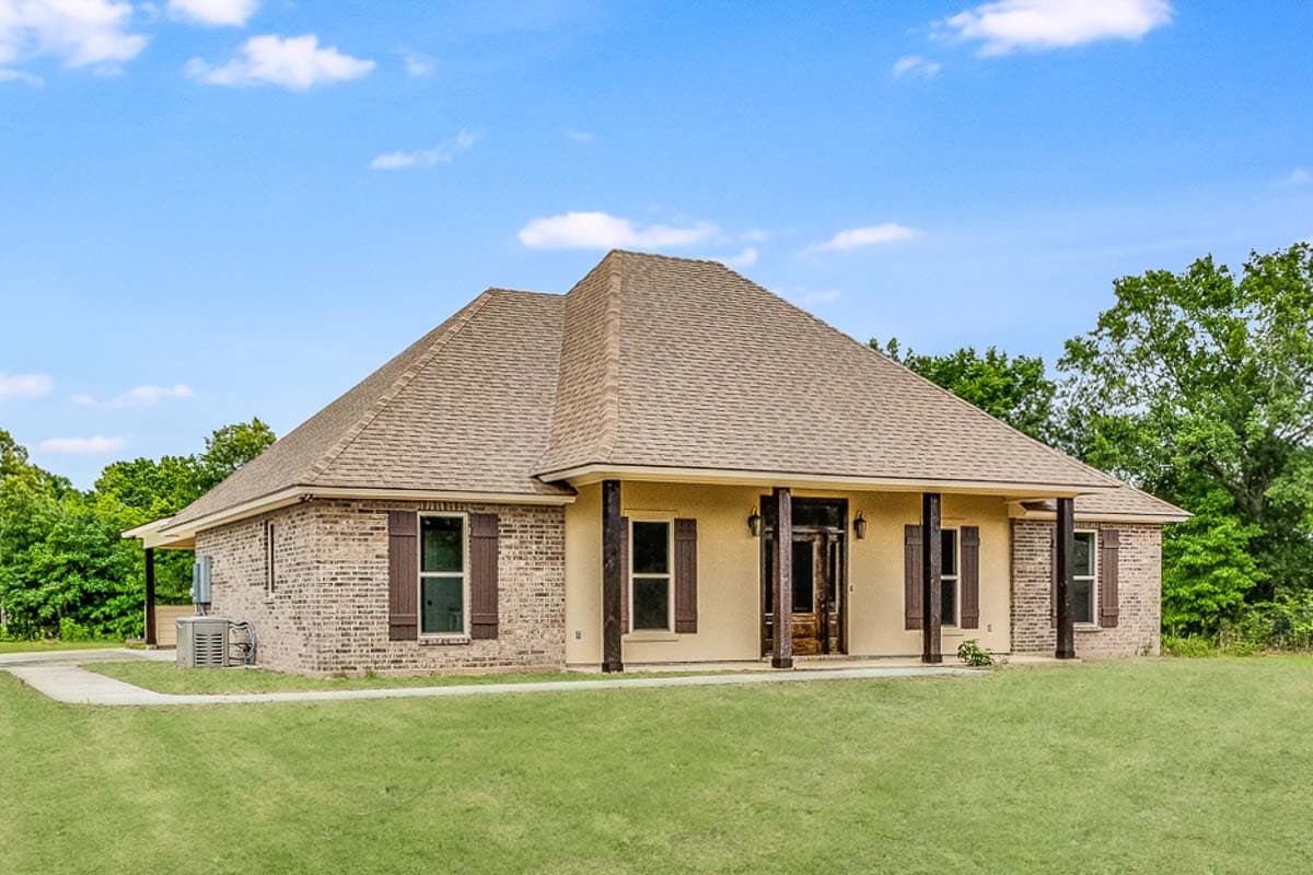 One-story house plan exterior with brick and stucco facade, covered front porch supported by dark wood columns, and hip roof.