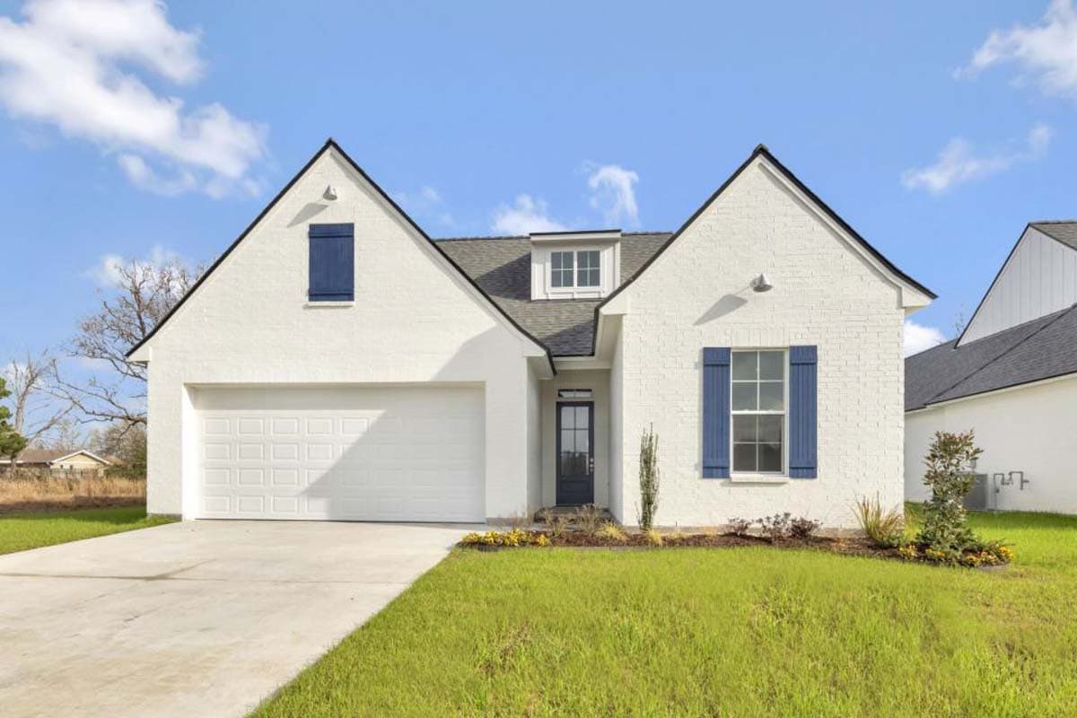 House plan exterior. One-story house with a gabled roof, dormers, and a two-car garage. Features include blue shutters and a brick facade.
