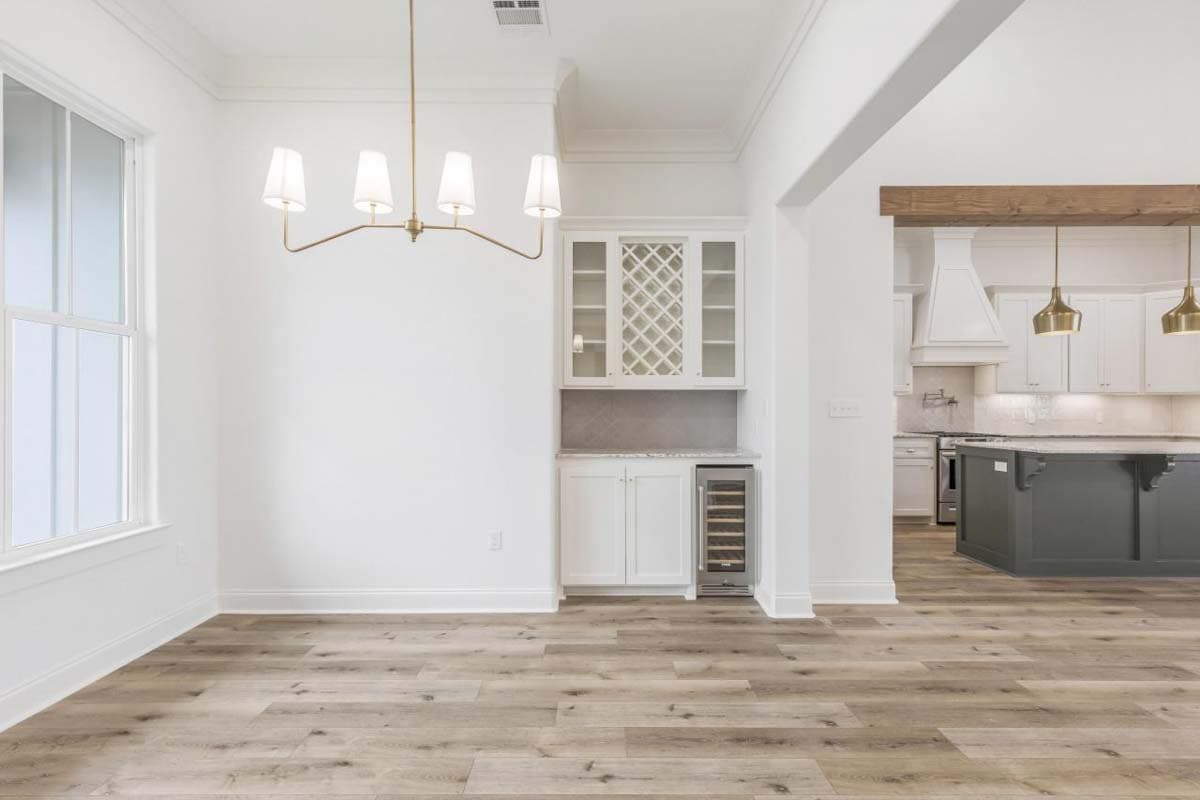 Interior view of open concept living space featuring a wine bar cabinet, wood plank flooring, and kitchen with island and range hood.