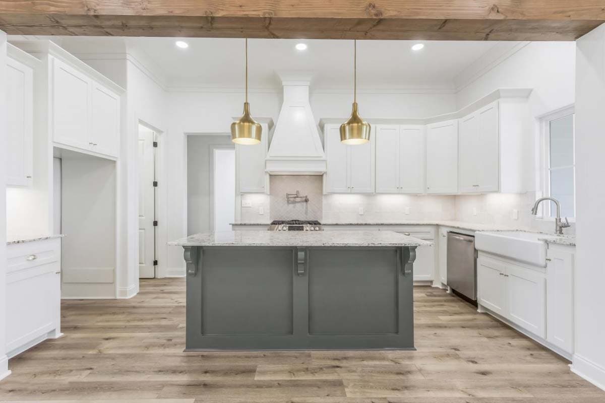 Kitchen with large island, white cabinets, farmhouse sink, pendant lights, and exposed wood beams.