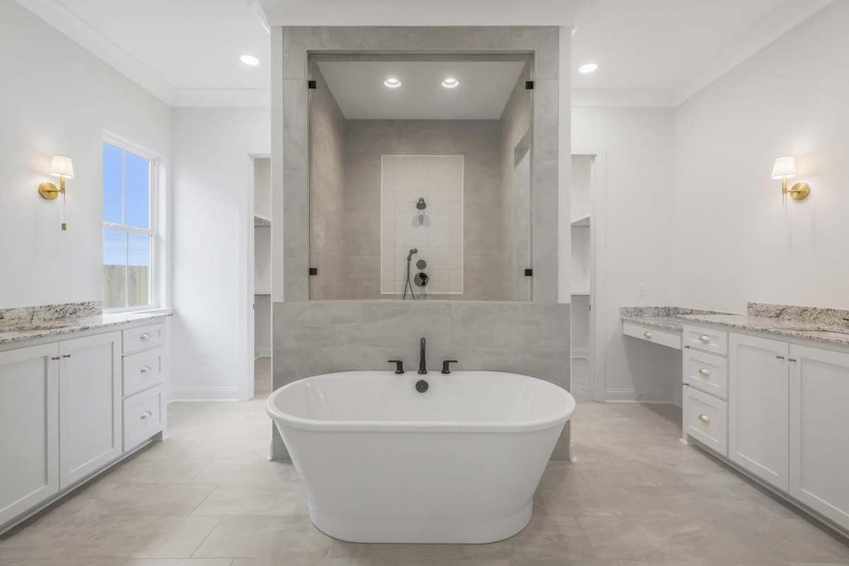 Freestanding tub in bathroom with dual vanities, glass-enclosed shower with tiled walls, and central shower fixture.