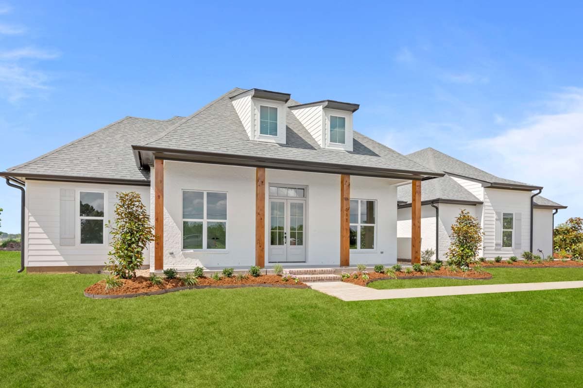 House plan exterior: White stucco and lap siding, prominent gables, dual dormers, and wooden porch columns supporting a dark roof.