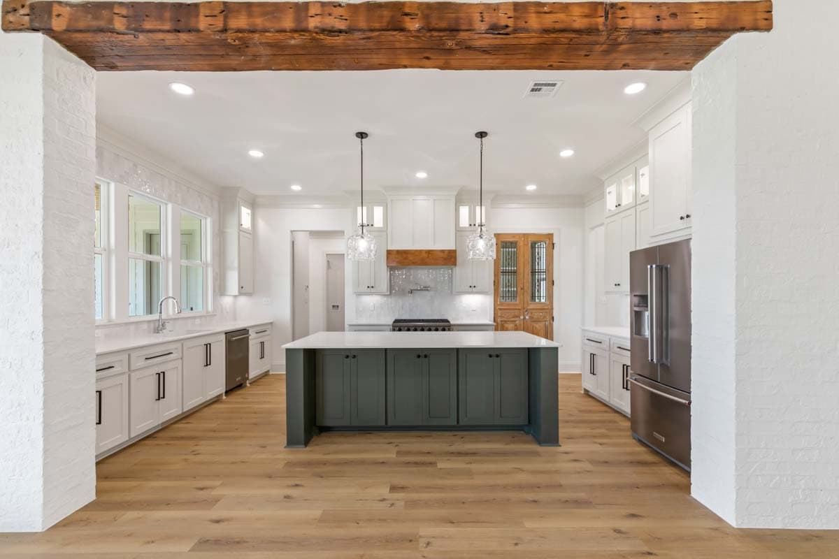 Kitchen with island, white cabinetry, stainless steel appliances, and wood beam ceiling detail.