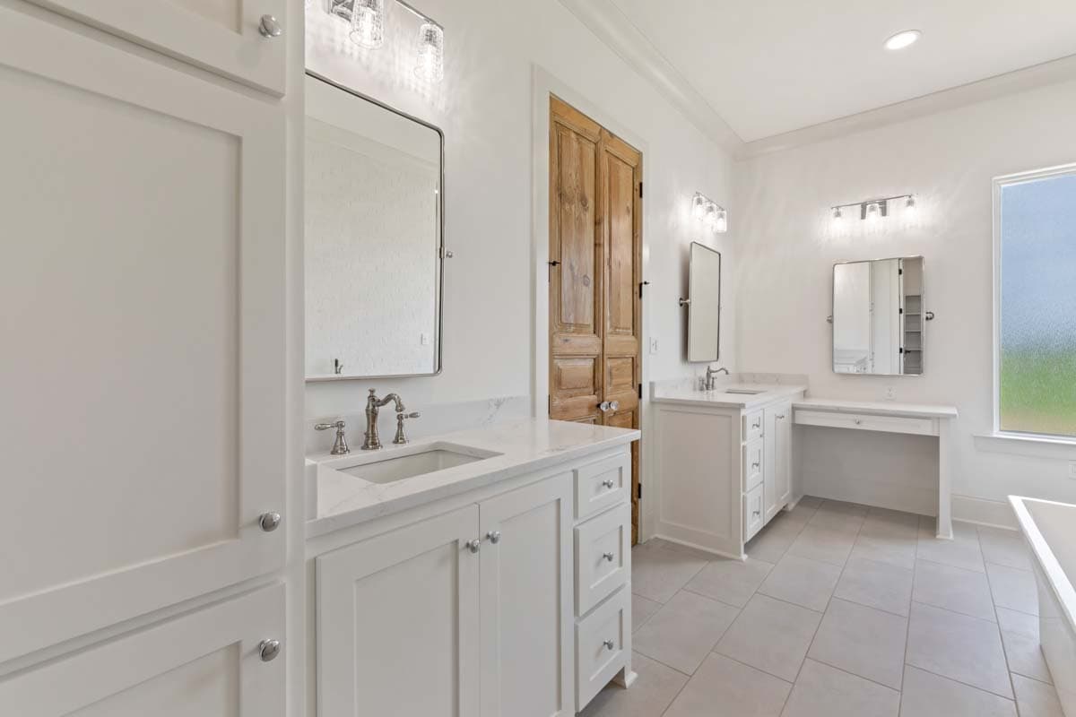 Bathroom with double vanity, vanity desk, wood double doors, and tiled floor.