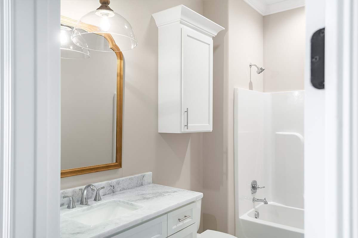 Bathroom vanity with marble countertop, sink, and medicine cabinet above. Bathtub and shower unit visible.