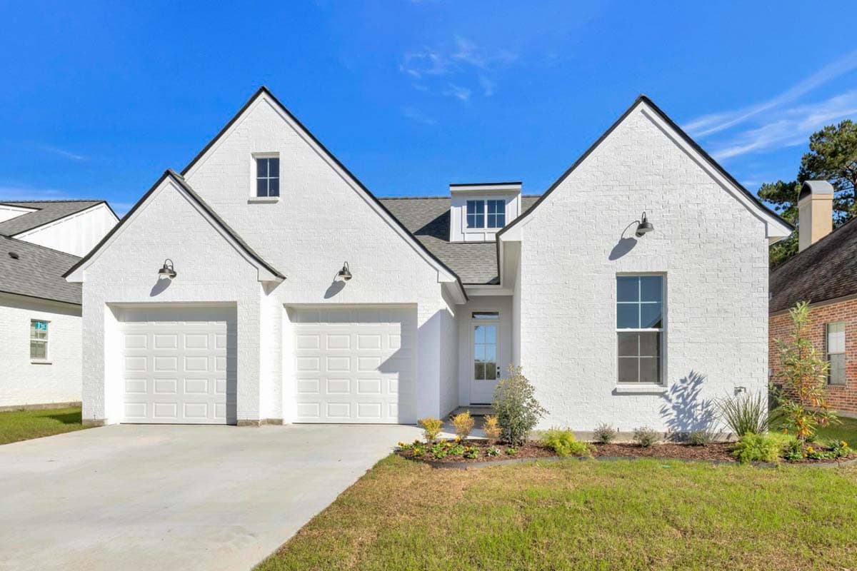 House plan exterior features white brick, a dormer, gables, and a side-entry two-car garage.