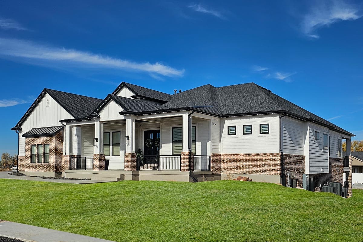 Modern Farmhouse house plan exterior with brick and white siding, a covered porch with columns, and multiple gables.