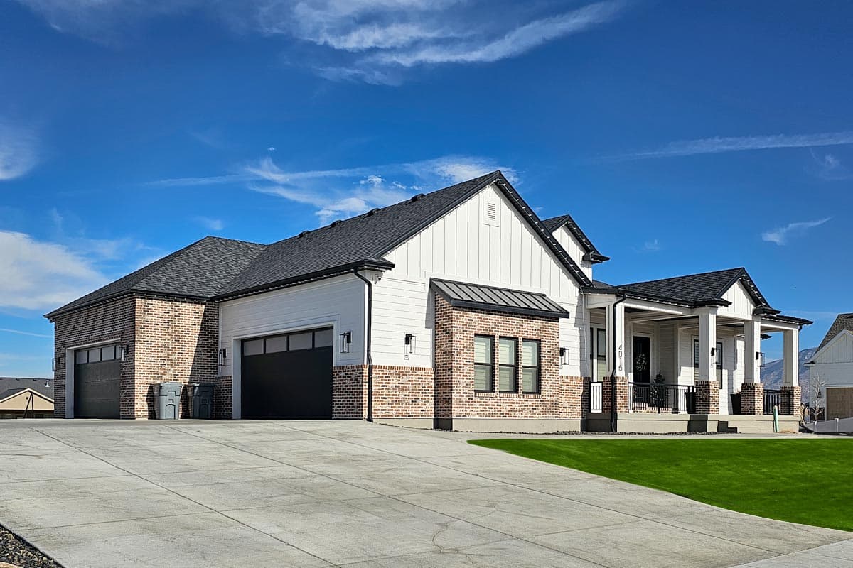 Modern Farmhouse house plan exterior with brick and siding, multi-level roof, a covered porch with columns, and a three-car garage.