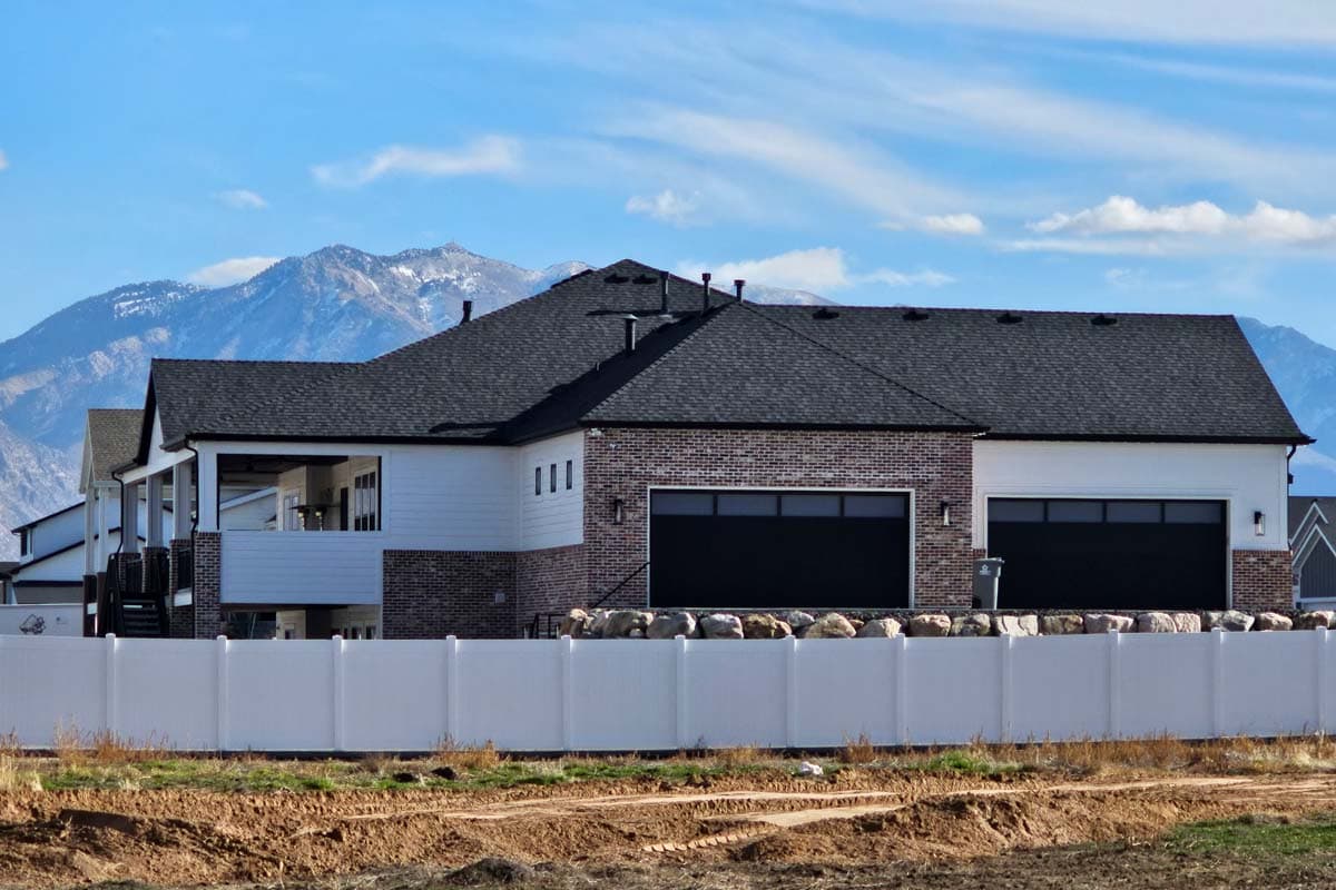 Modern house plan exterior with brick and white siding, covered porch, and a three-car garage with black doors.