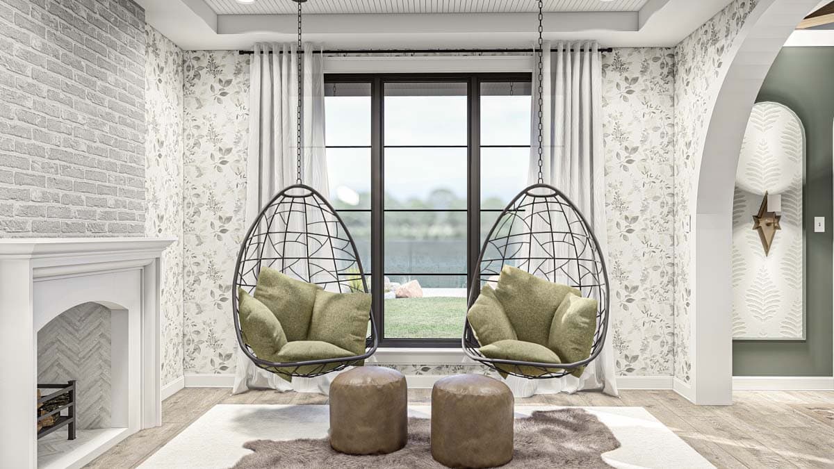 Interior view of a sitting area with two hanging chairs, a fireplace with arched opening, and a large window.