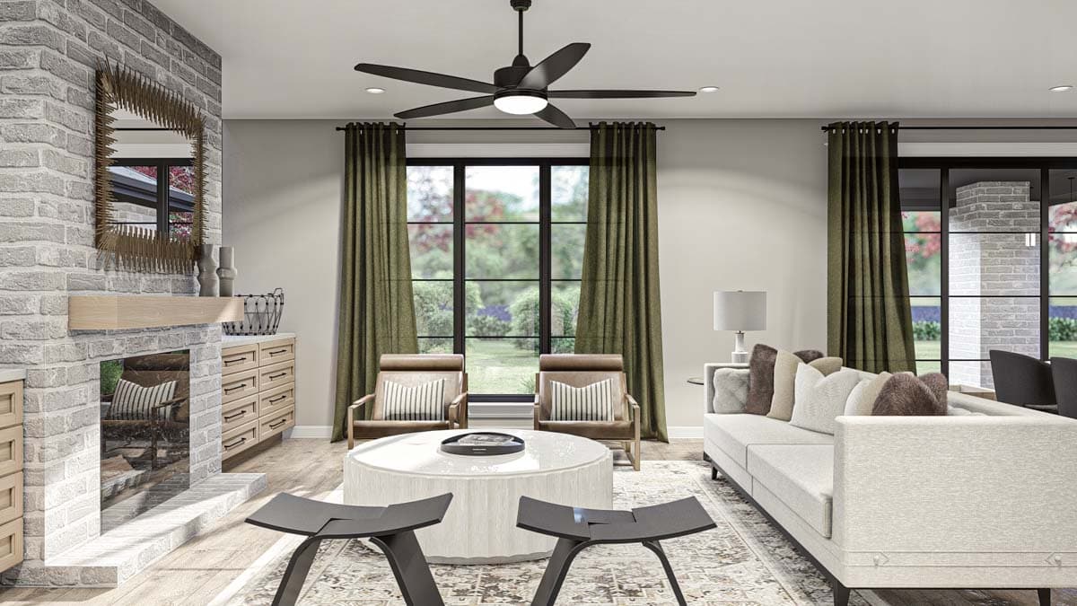 Living room with brick fireplace, sectional sofa, round coffee table, two armchairs, and large windows with garden view.