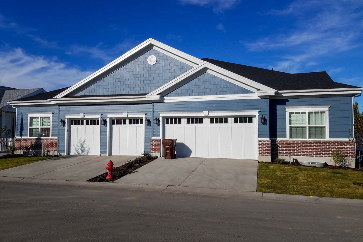 House plan exterior with blue siding, white trim, three-car garage, and gable dormers.