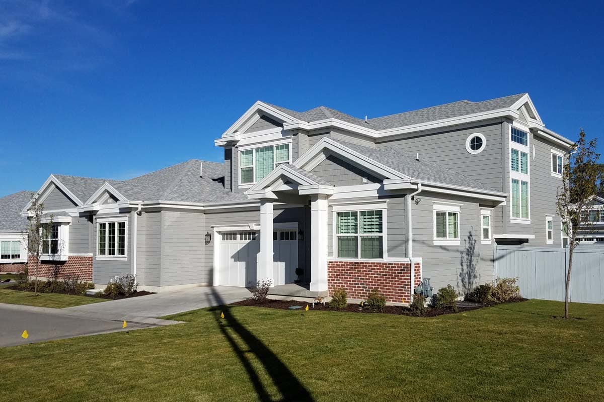 House plan exterior: Modern style, two stories, hip roof, gabled dormers, covered entry, and two-car garage.