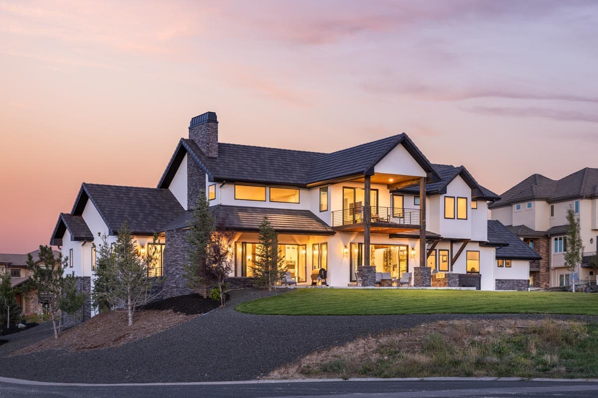 House plan exterior: Modern home with stone chimney, multiple gables, balconies, and large windows.