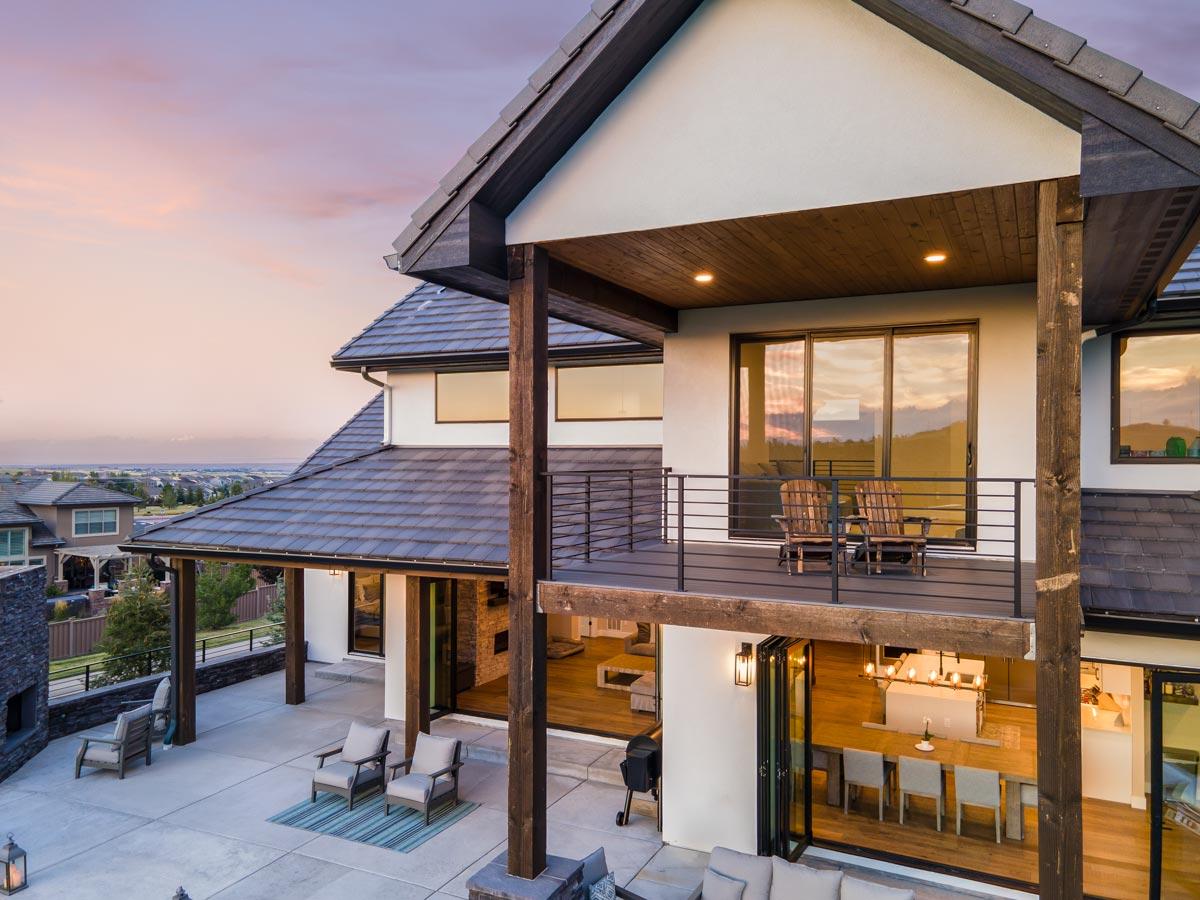 Exterior view of a modern house plan with multiple gables, covered patios, and a second-story balcony.