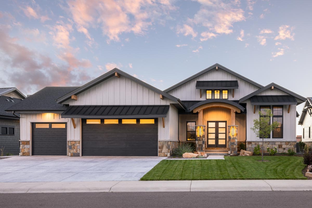 House plan exterior with board and batten siding, gable roof, and two garage bays with dark doors and stone accents.