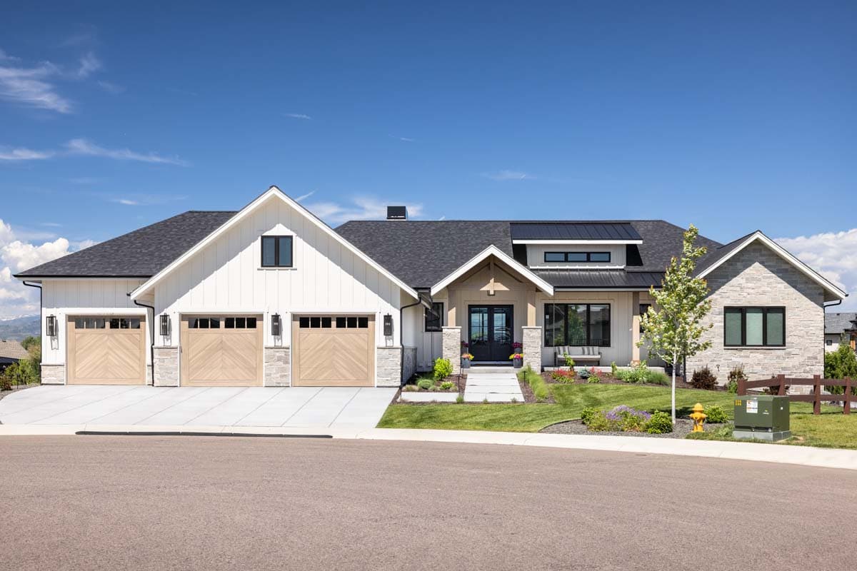 House plan exterior. Modern Farmhouse style with two stories, three-car garage, gabled rooflines, and stone accents.