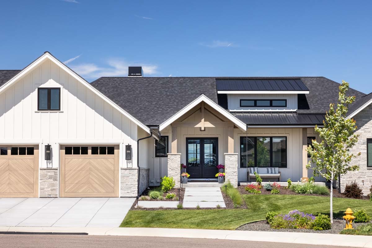 Modern Farmhouse house plan exterior with white board and batten siding, stone accents, double garage, and covered entry.
