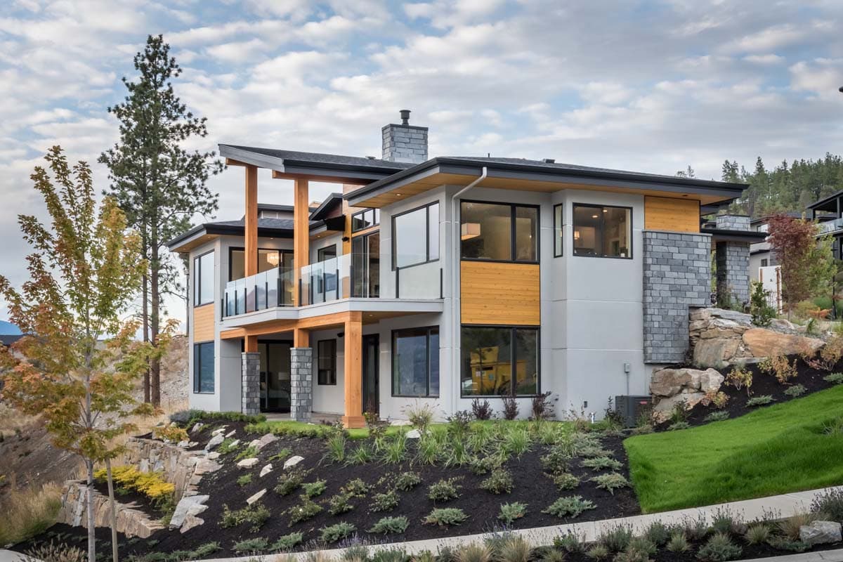 Modern multi-story house plan exterior with cantilevered balconies, wood accents, stone chimney, and large windows.