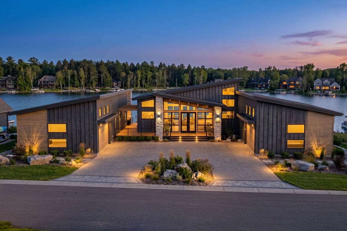Modern house plan exterior with intersecting rooflines, stone accents, and large windows flanking a central entry.
