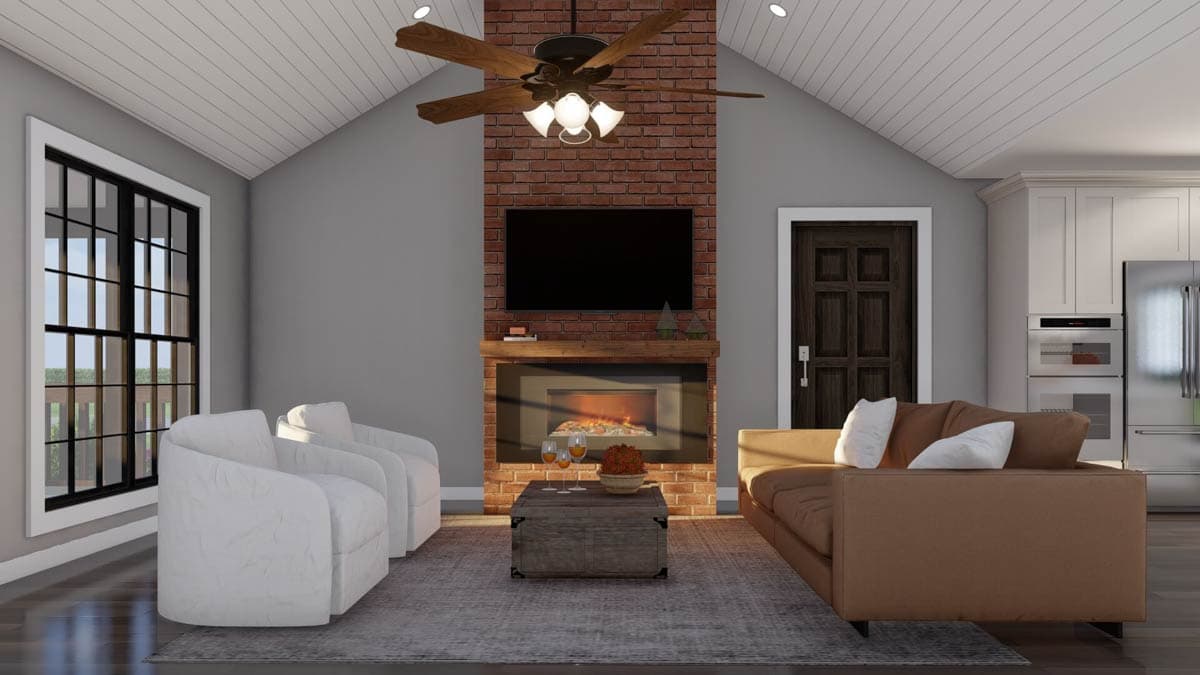 Great room with vaulted ceiling, brick fireplace and entertainment center, and adjacent kitchen with white cabinets and stainless steel appliances.
