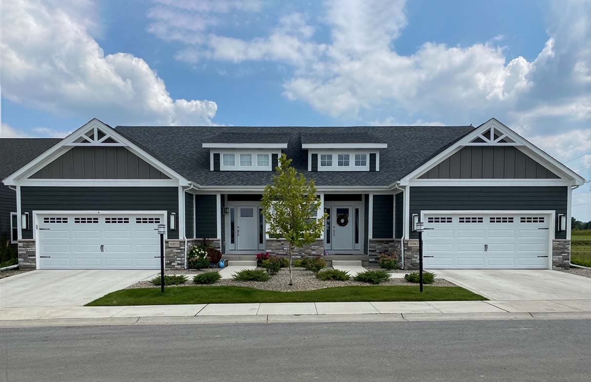 House plan exterior featuring a symmetrical design with two garages, gabled dormers, and stone accents.