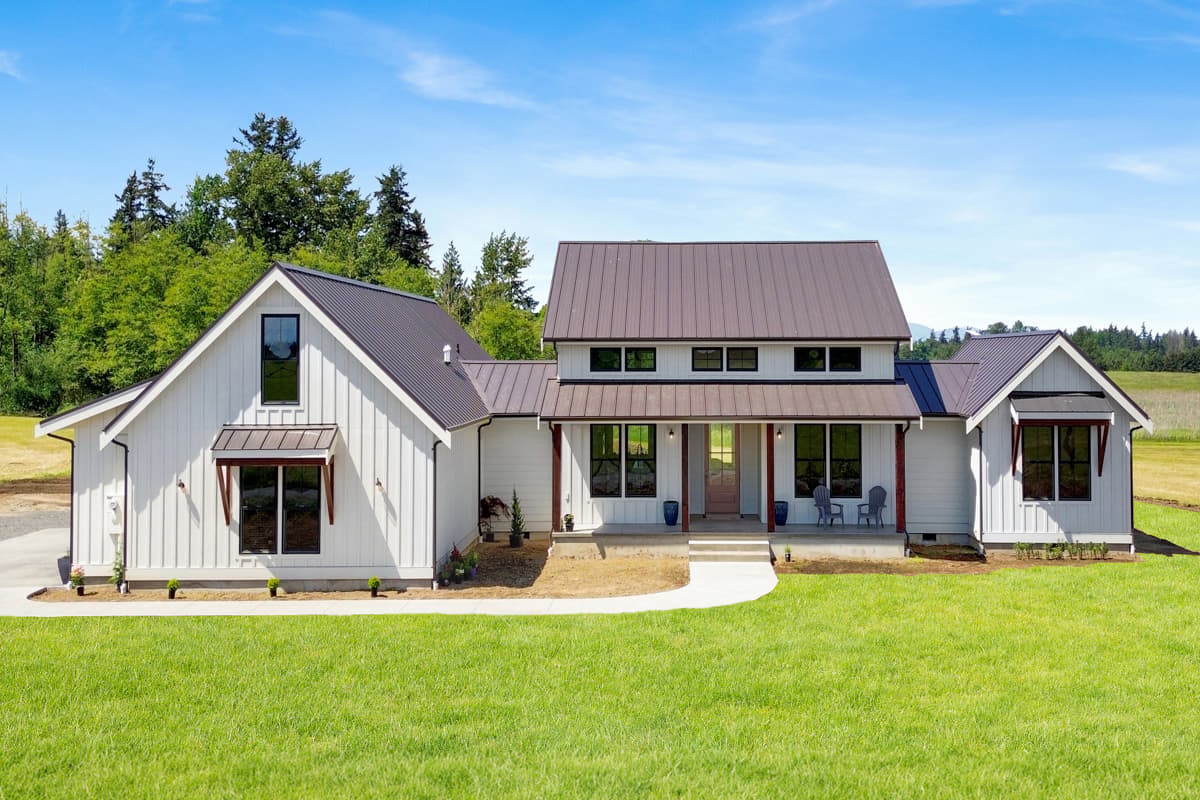 Modern Farmhouse exterior with white board and batten siding, metal roof, and a covered front porch with dark beams.