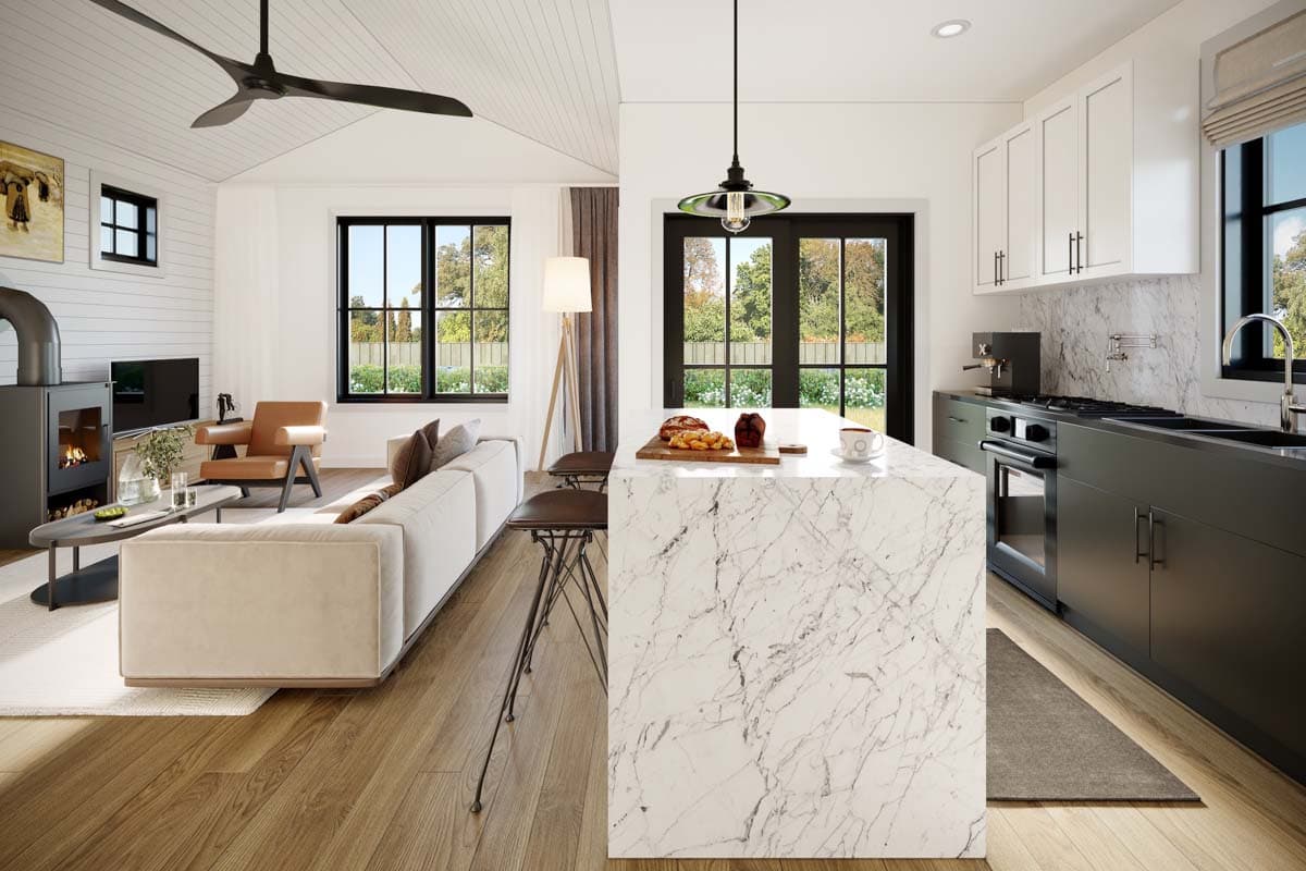 Open concept living area with vaulted ceiling, wood stove, sofa, and kitchen island with seating.