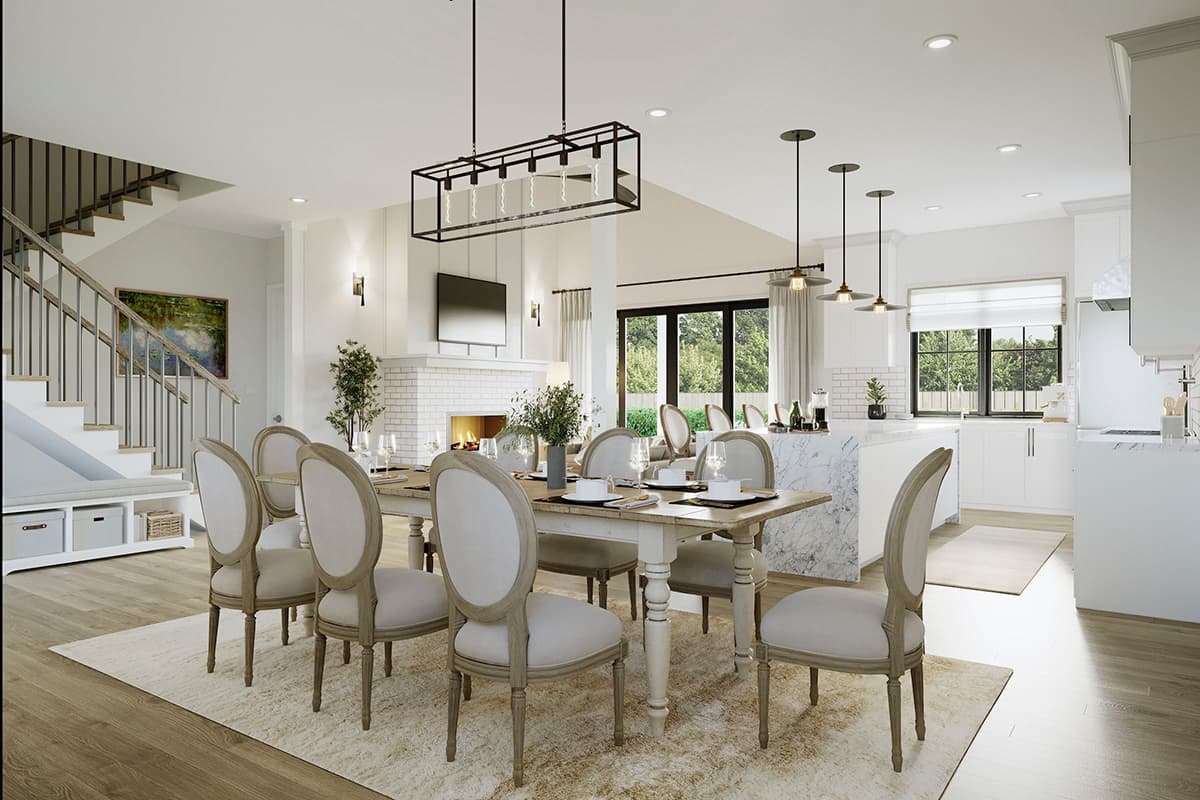 Open-concept dining and kitchen area with fireplace, island, and staircase. Contemporary chandelier hangs over dining table.