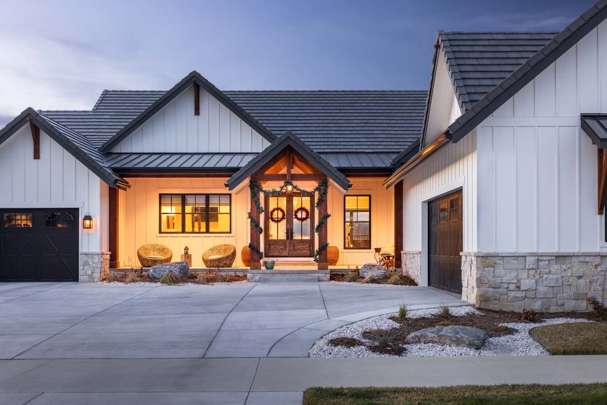 Modern Farmhouse house plan exterior with white board and batten siding, stone accents, multiple gables, and two-car garage.