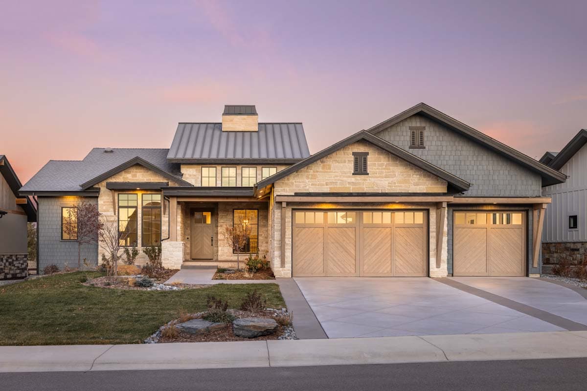 House plan exterior showing a Modern Farmhouse style, two-story home with stone and shingle siding, metal roof, and a three-car garage.