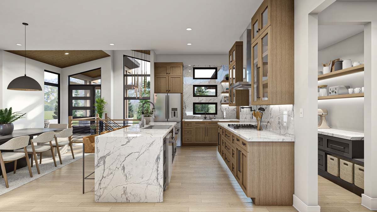 Modern open-plan kitchen with wood cabinetry, marble countertops, and an island. A dining area and pantry are also visible in the spacious interior.