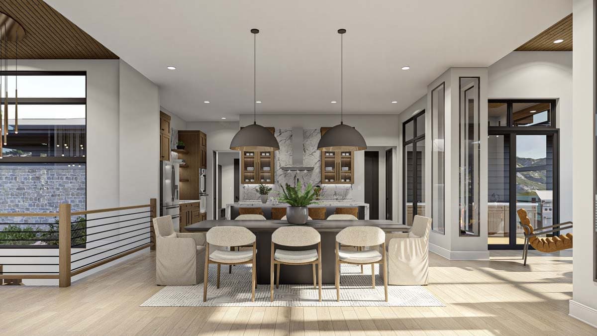 Modern open-concept dining area with a long table, chairs, and two pendant lights. A kitchen with marble countertops sits in the background.