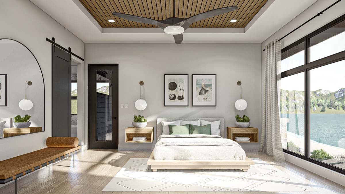 A modern bedroom features a light-colored wooden bed frame, bedside tables, and a large window overlooking a lake. Decorative art hangs on the wall.