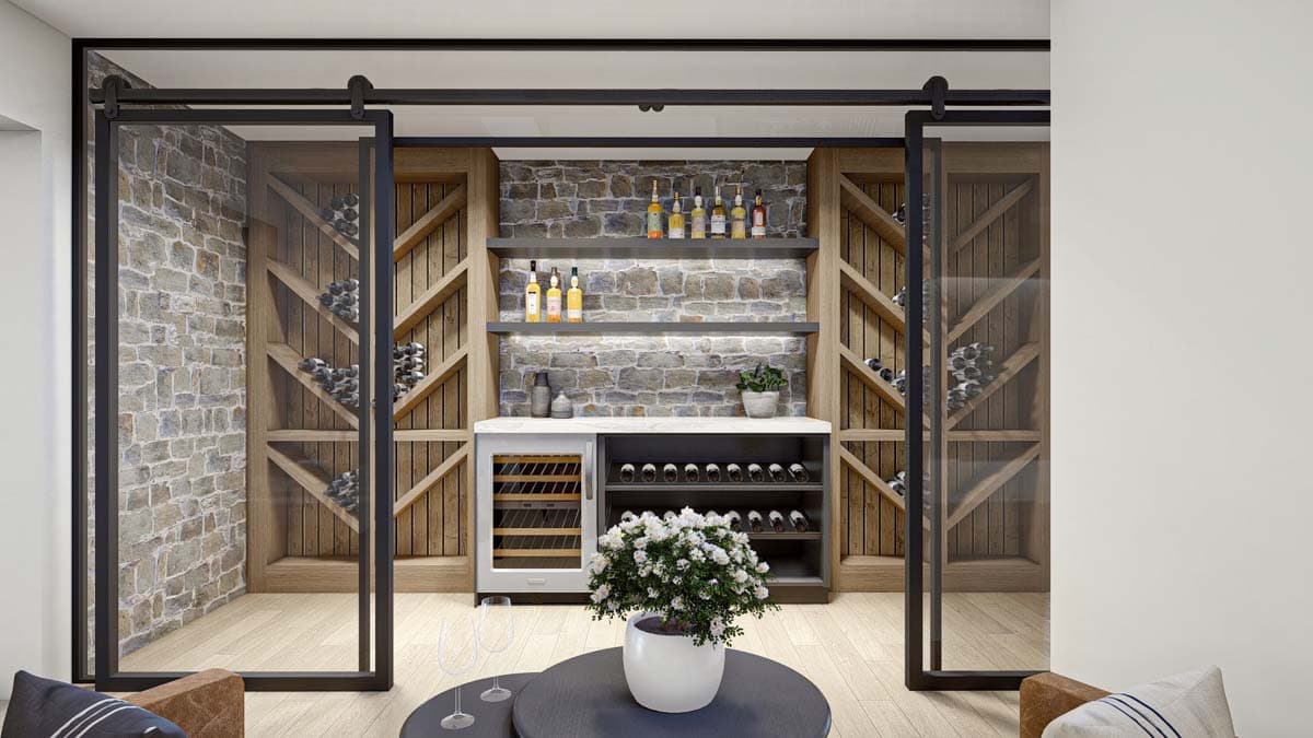 A modern wine cellar with stone accent wall and glass sliding doors. Bottles and bar setup sit behind a white countertop with a flower arrangement.