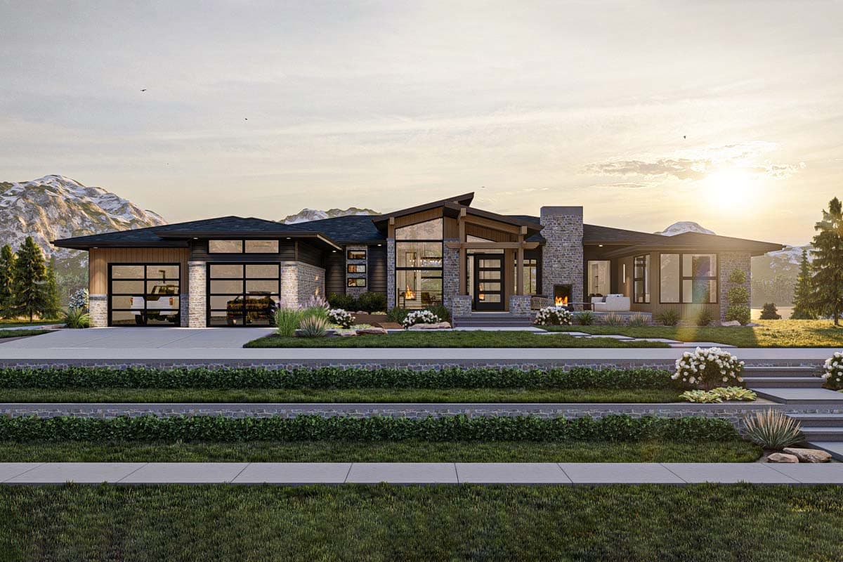 A modern, luxury home with large windows, a stone fireplace, and a glass-paneled garage. Mountains and sunset in the background.
