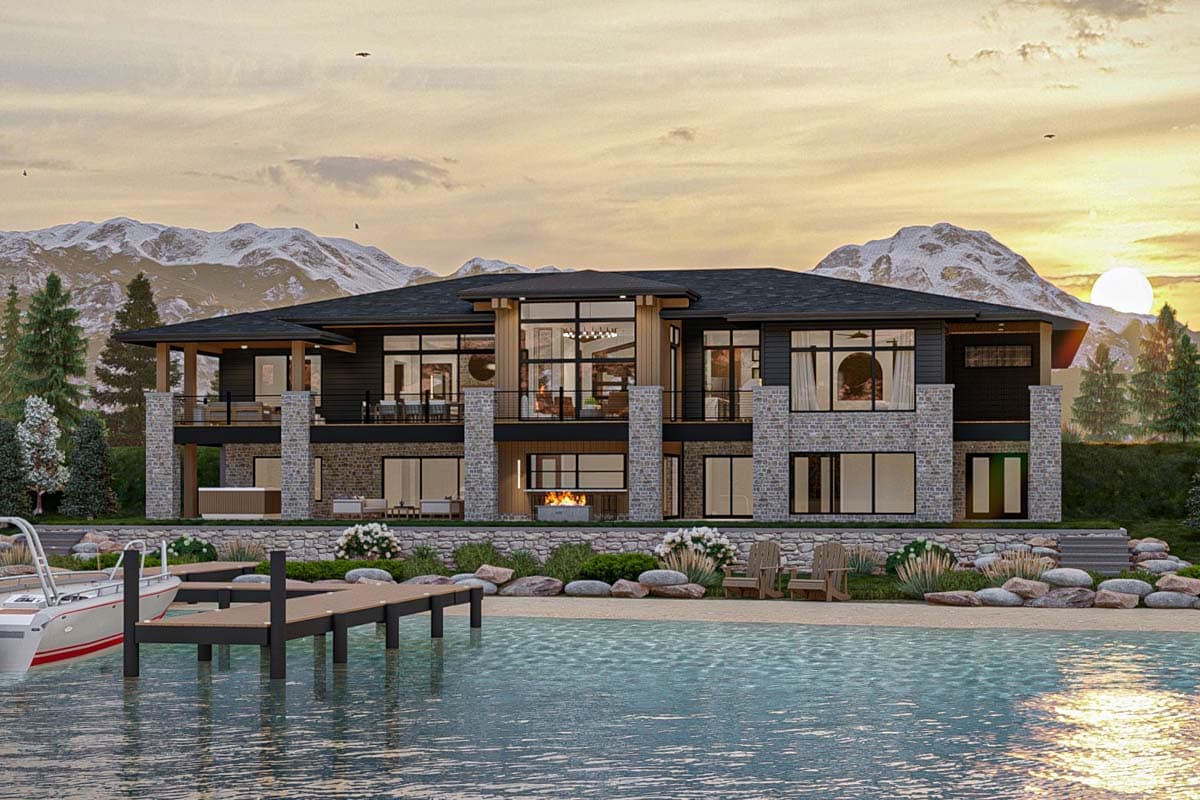 A modern lakeside house with a wooden dock, set against a backdrop of mountains and a sunset sky. The house has large windows and a stone exterior.