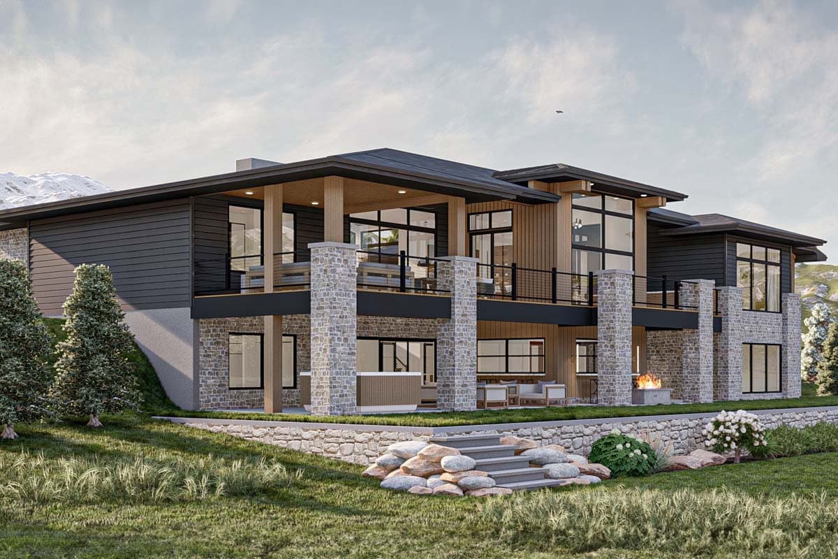 Modern multi-story home with stone columns, dark siding, and large windows. Features include a wraparound deck, outdoor fireplace, and mountain views.