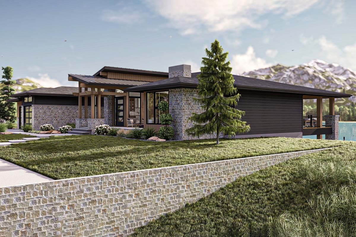 A modern, single-story house featuring stone and dark wood siding, situated on a grassy landscape with a lake view in the background.