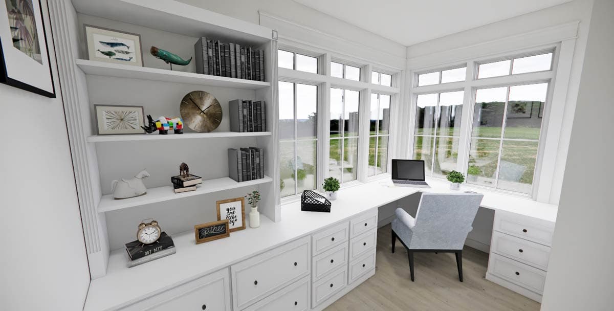 A bright home office with a white built-in desk and shelving. A laptop sits on the desk near a large window overlooking a green yard.
