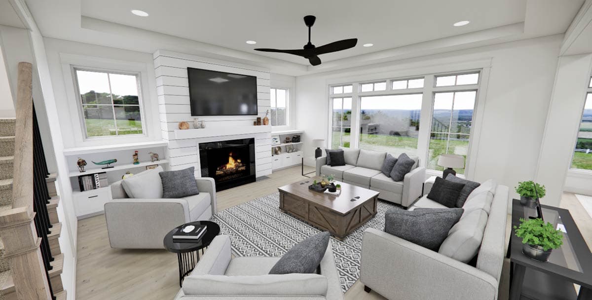 Spacious, modern living room with a fireplace, large windows, and neutral-toned furniture. A black ceiling fan hangs above the seating area.