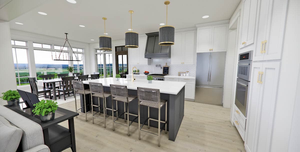 Spacious, modern kitchen with a large island, pendant lights, and stainless steel appliances. A dining area and outdoor view are also visible.