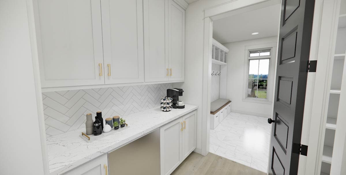 A modern, well-lit kitchen pantry with white cabinets, a coffee machine, and a view into a hallway with a bench and window.
